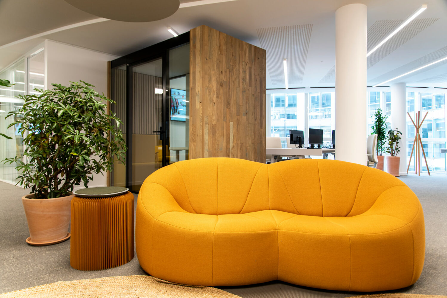 Un canapé design d'un jaune éclatant apporte une touche de luminosité dans les bureaux